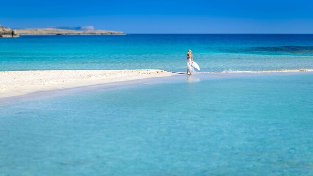 Una playa con agua turquesa cristalina y una orilla arenosa.