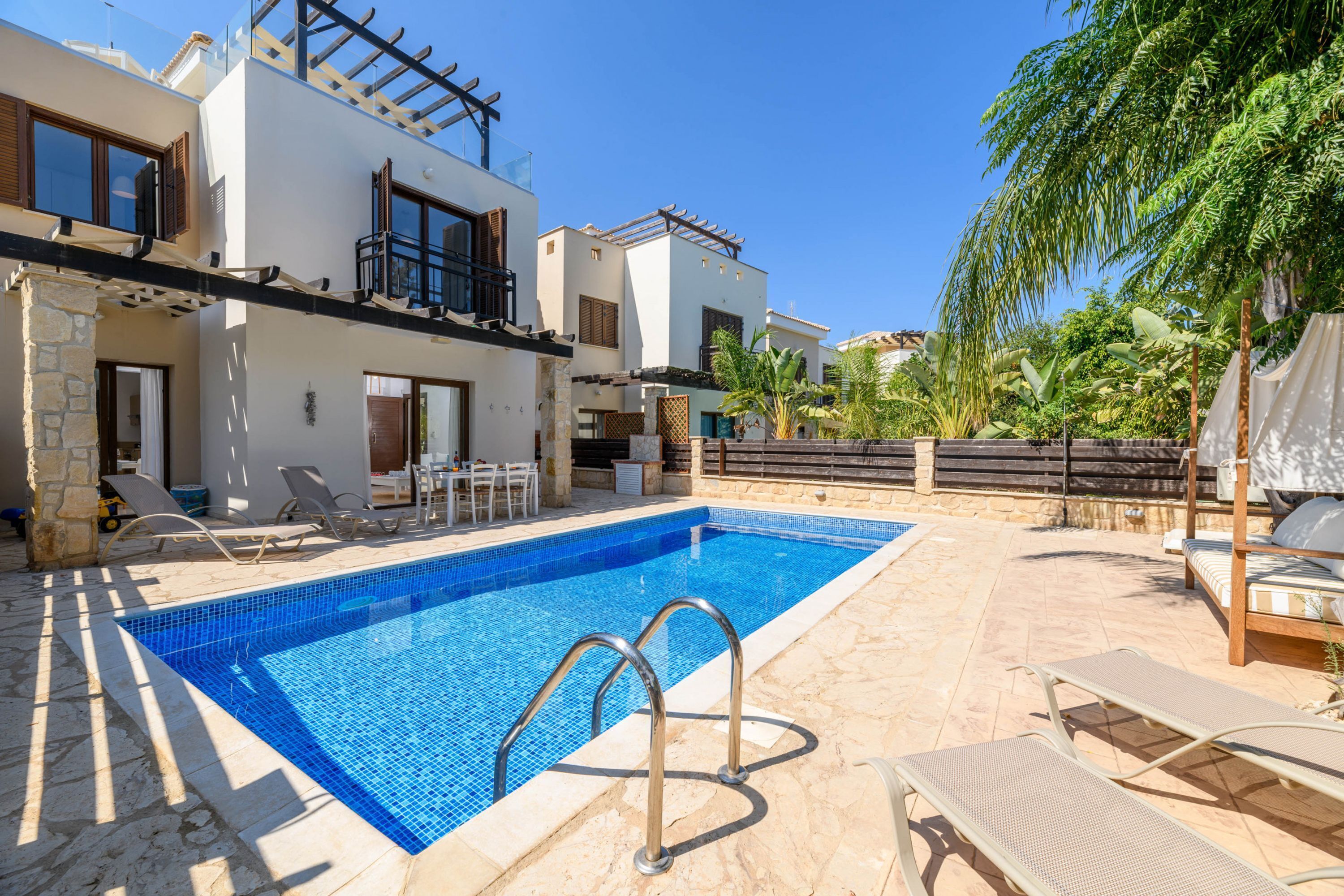 A swimming pool with lounge chairs and a pergola.