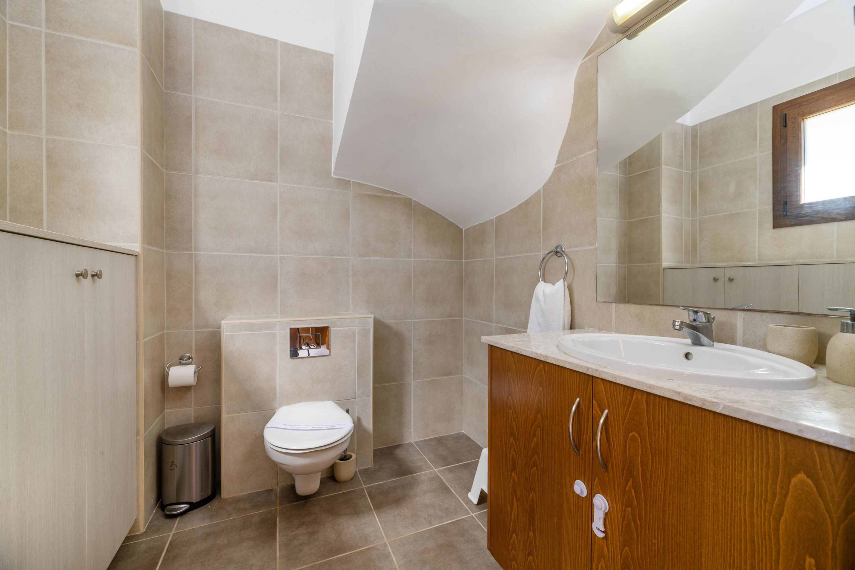 Un baño moderno con inodoro, lavamanos y espejo.