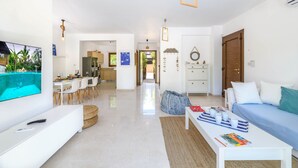 A modern living room with a TV, sofa, coffee table, and dining area. - Villa Greco Mare 40 (Paralimni)