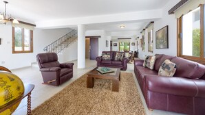 A spacious living room with a high ceiling, a staircase, and a large window. - Villa Sam in Ayia Napa (Ayia Napa)