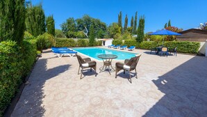 A pool area with lounge chairs, a table, and a blue umbrella. - Villa Sam in Ayia Napa (Ayia Napa)