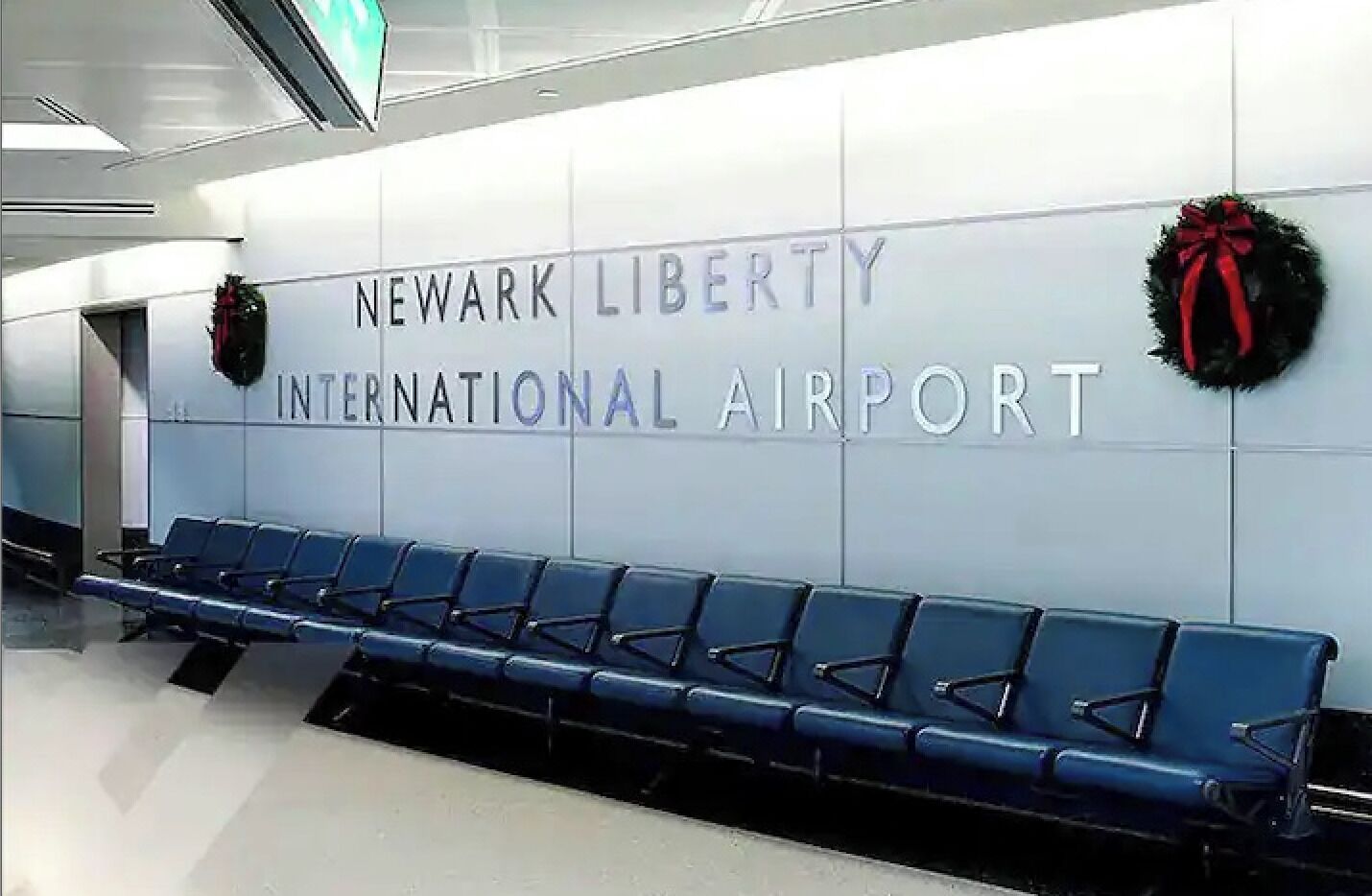 Ein Terminal des Newark Liberty International Flughafens mit blauen Sitzreihen und Weihnachtsgestecken an der Wand.