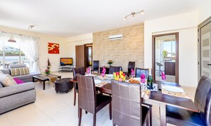 A modern living room with a dining area, a TV, and a view of the outdoors. - Villa Marizan in Protaras (Paralimni)