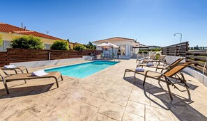 A rooftop pool area with lounge chairs, a covered seating area, and a clear view of the surrounding landscape.