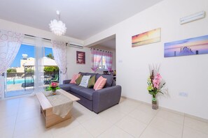 A modern living room with a grey sofa, a wooden coffee table, and a vase of flowers.