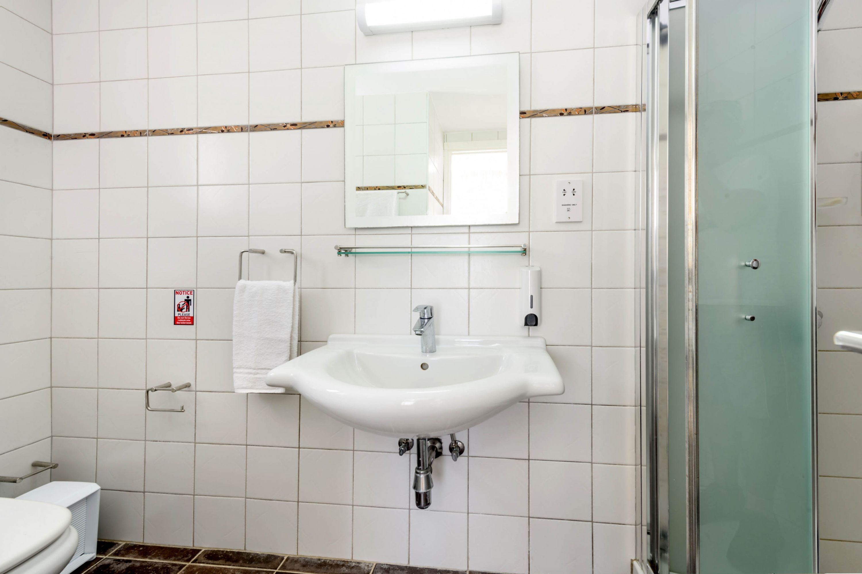 Ein Badezimmer mit Waschbecken, Spiegel und Duschkabine aus Glas.