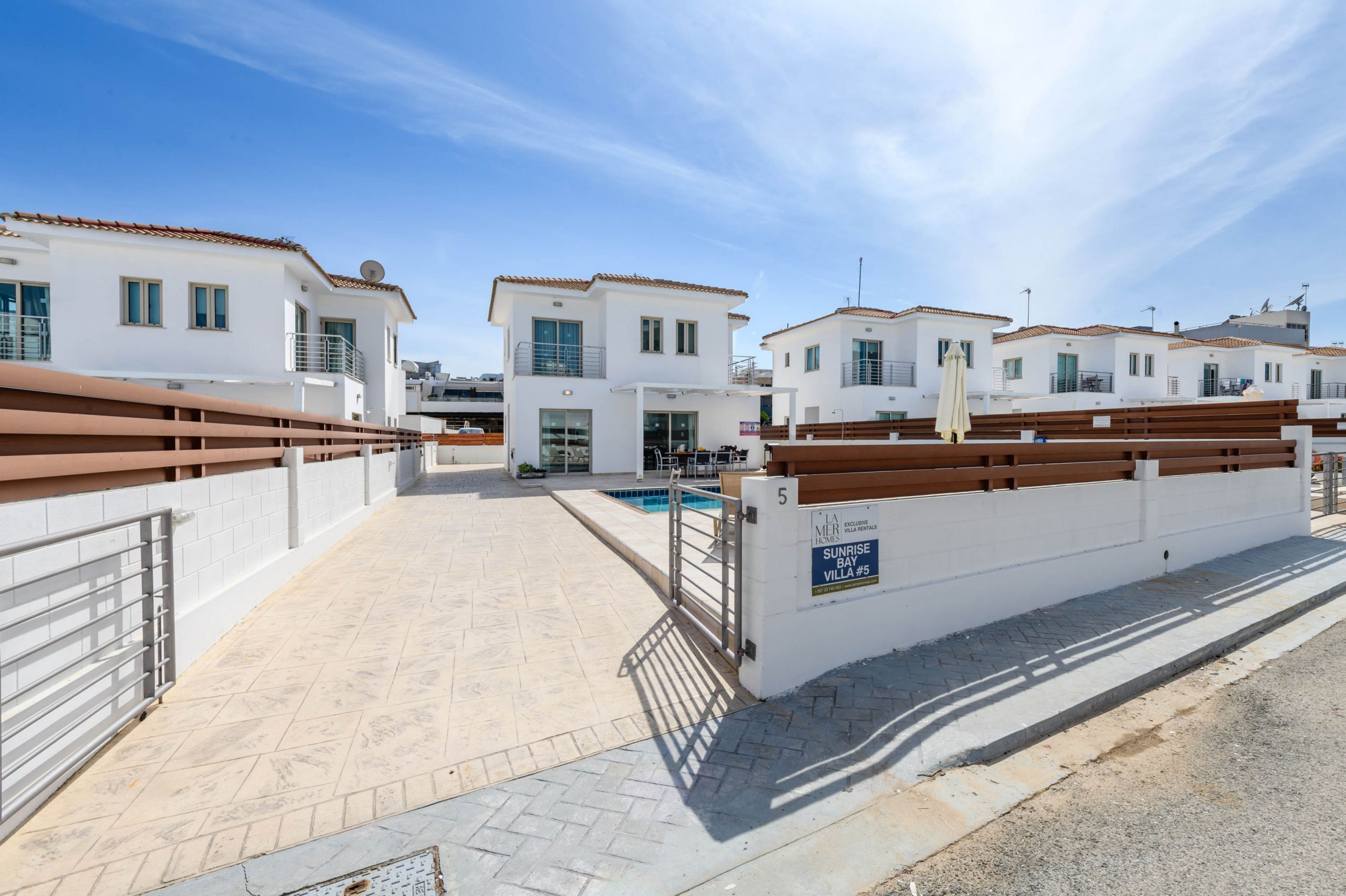 A modern villa with a swimming pool, white walls, and a tiled roof.