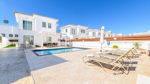 A modern villa with a swimming pool, outdoor seating, and a clear blue sky. - Sunrise Bay Villa 6 (Paralimni)
