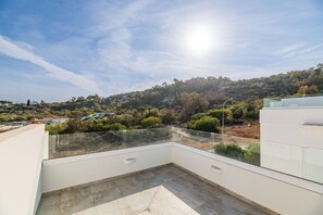 A rooftop terrace with a clear view of a hilly landscape, a water park, and a white building. - Green Bay Villa 17 in Protaras (Paralimni)