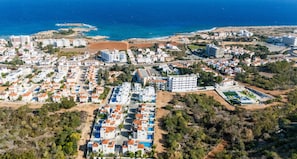 An aerial view of a coastal resort with multiple buildings, a beach, and a marina.