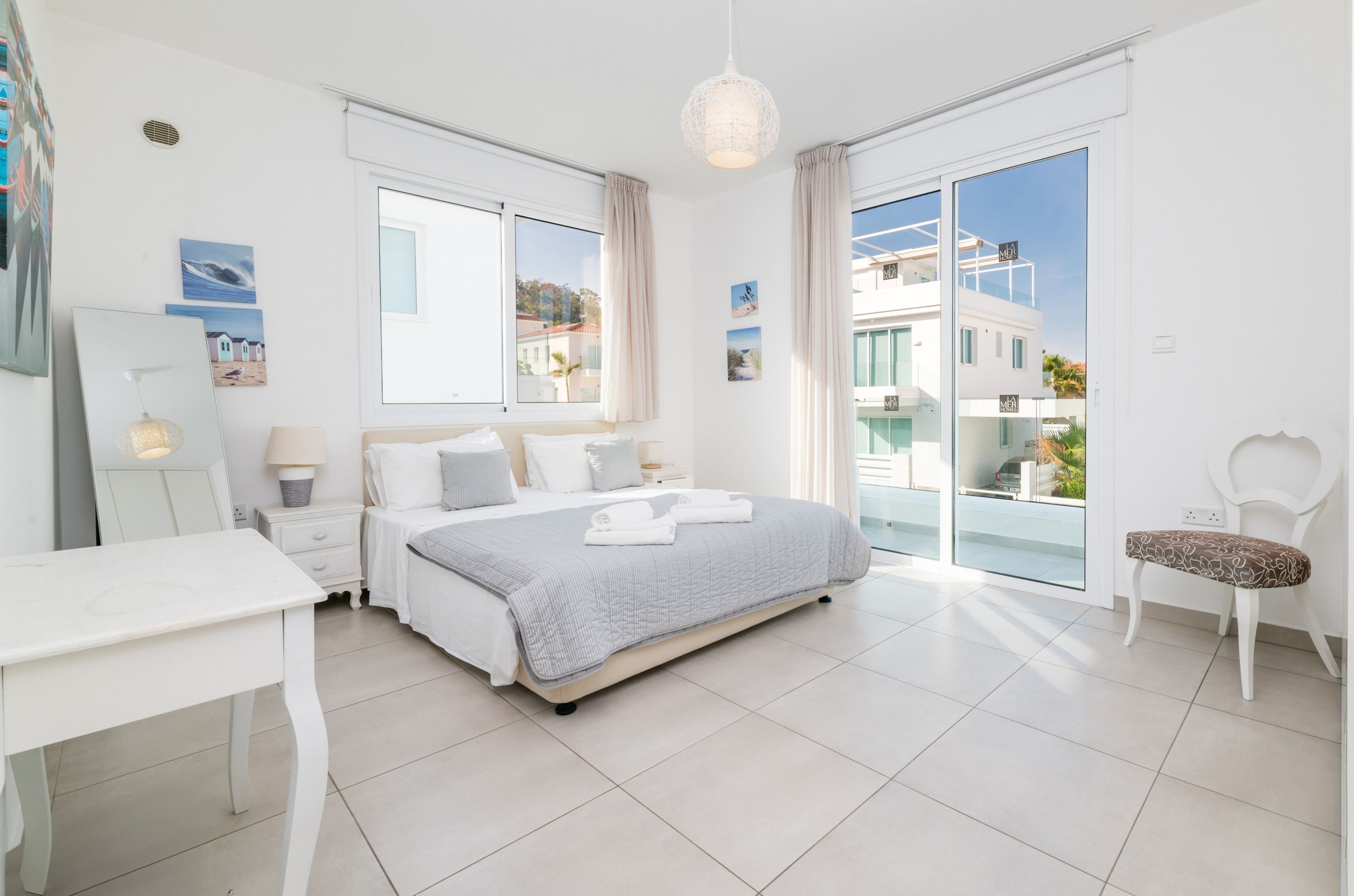 A modern bedroom with a bed, bedside tables, a desk, and a chair.