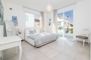A modern bedroom with a bed, bedside tables, a desk, and a chair.