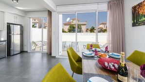 A modern kitchen with a built-in refrigerator and a dining area with a table set for two. - Green Bay Villa 17 in Protaras (Paralimni)