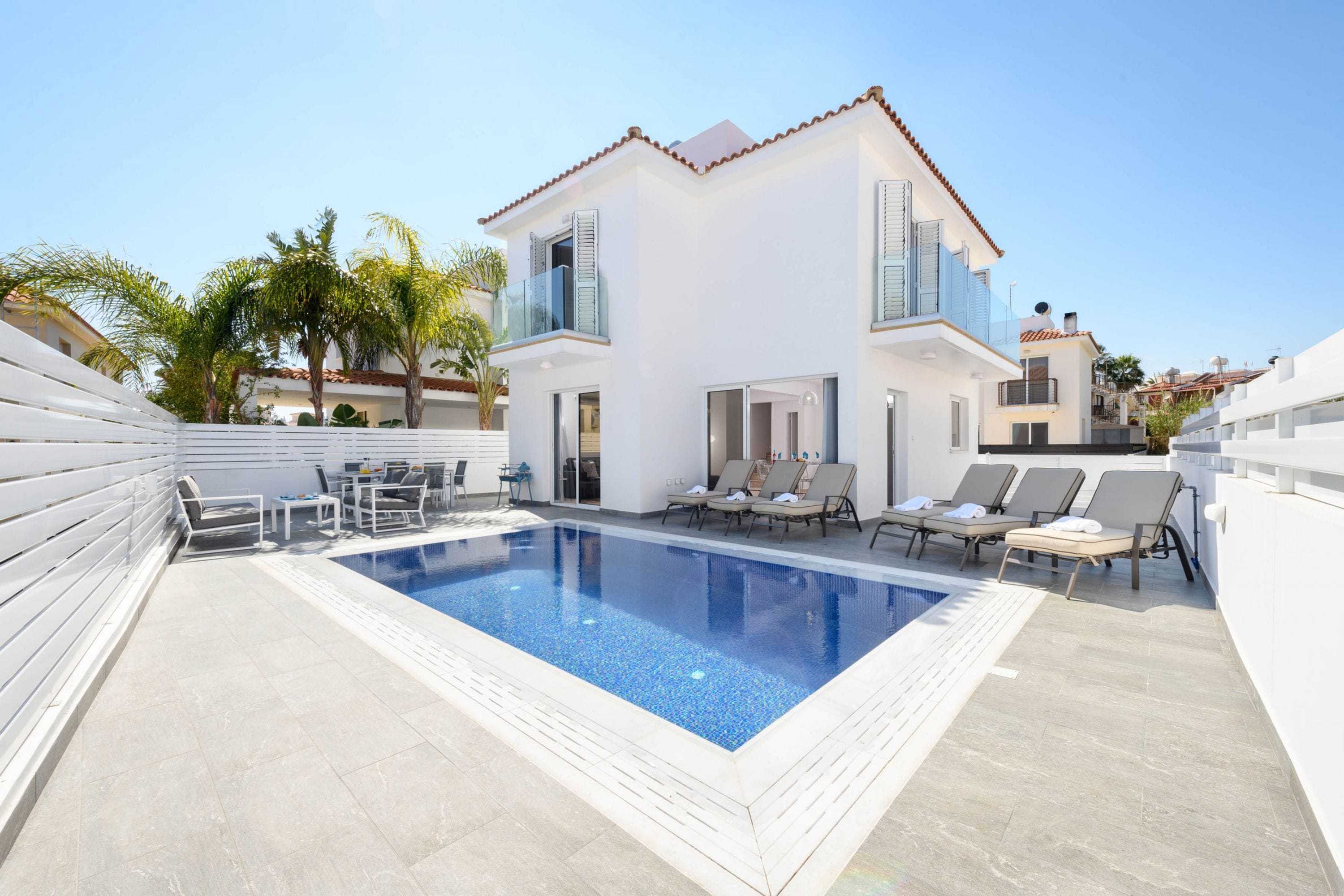 Une maison moderne à deux étages, dotée d’une piscine, d’un espace extérieur aménagé et d’une façade blanche.
