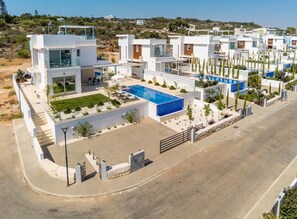 A modern residential complex with multiple houses, a swimming pool, and a well-maintained garden. - Mylos Lifestyle Seaview Villa 21 (Paralimni)