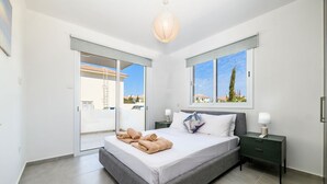 Une chambre à coucher moderne avec un grand lit, une table de chevet, une lampe et une vue sur l’extérieur.