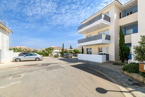 A modern apartment building with balconies, a parking area, and a clear blue sky. - Mythical Sands Ae01 in Protaras (Paralimni)