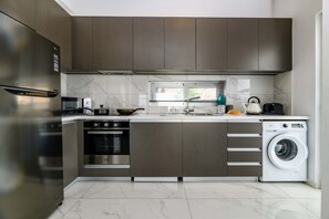 Una cocina moderna con electrodomésticos de acero inoxidable, horno empotrado, microondas y lavadora.