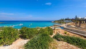 Uma área costeira com uma praia, um cais e um cal çadão com bancos.