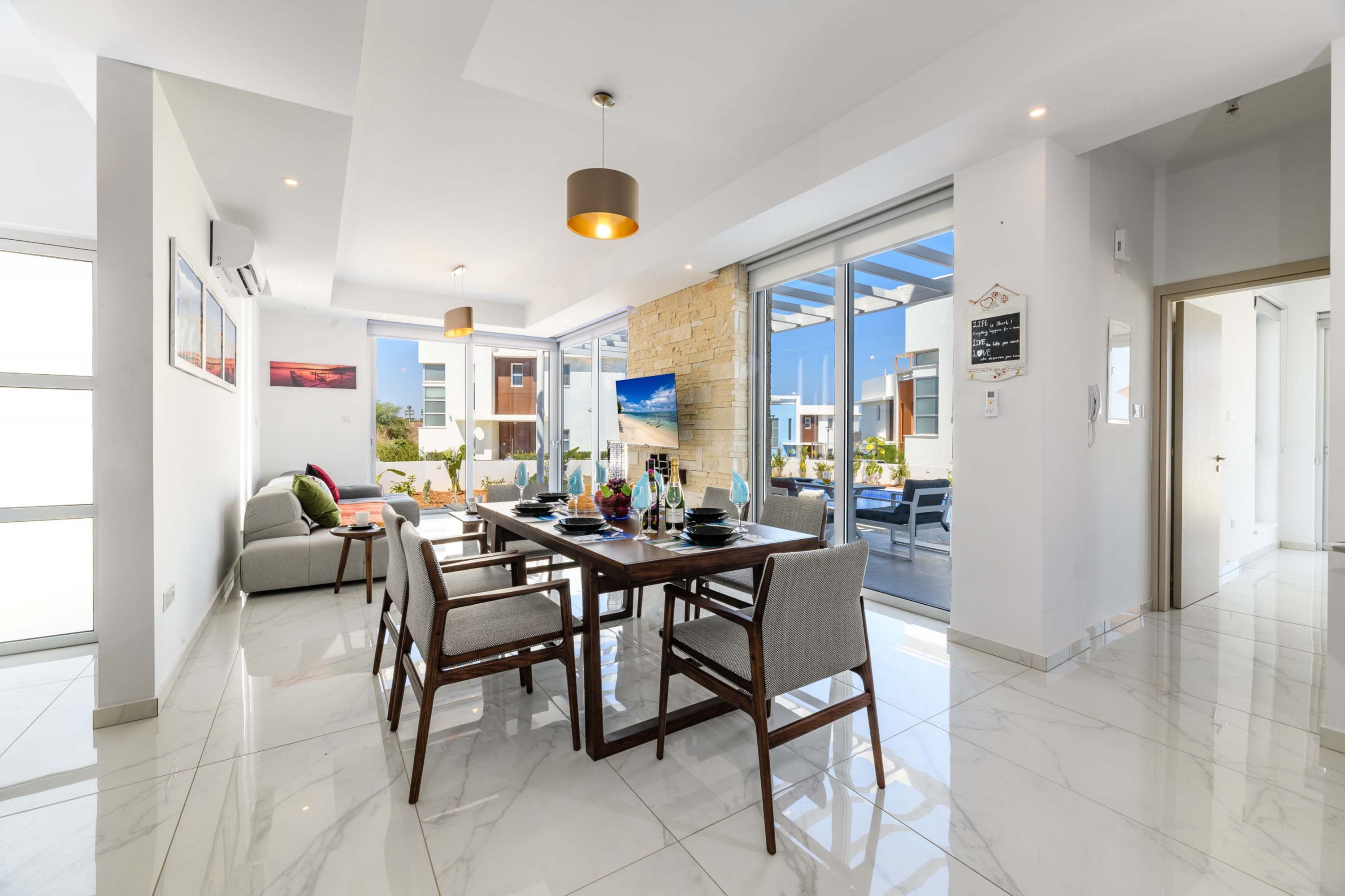 A modern dining area with a large table, chairs, and a television.