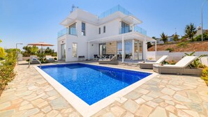 Uma casa moderna de dois andares com piscina, área de estar ao ar livre e varanda coberta.