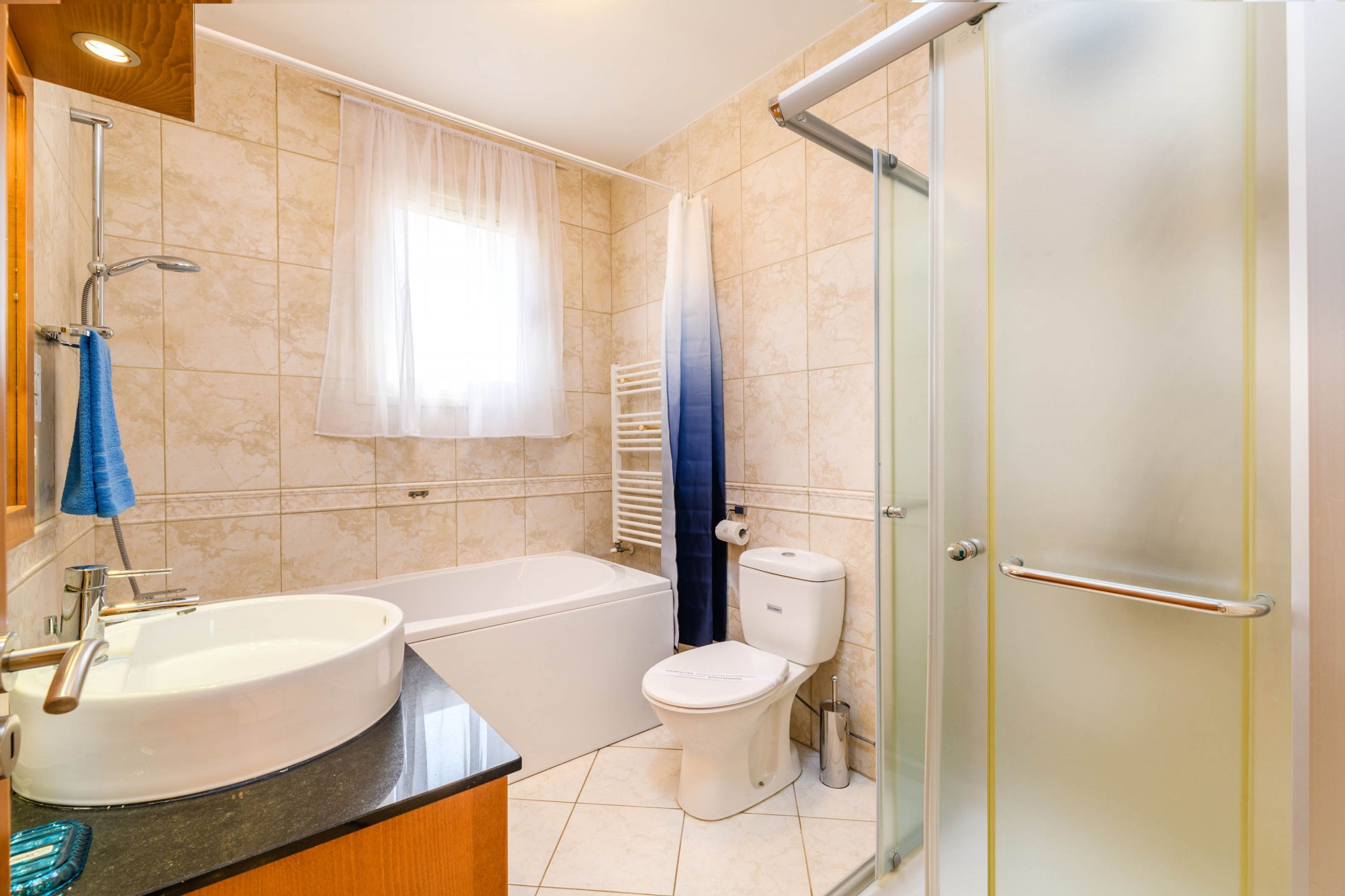 A bathroom with a sink, toilet, bathtub, and glass shower enclosure.