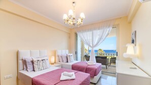 A hotel room with two beds, a balcony with a view, and a chandelier. - Royal Beachfront Villa (Paralimni)