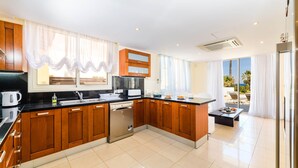 A modern kitchen with wooden cabinets, a dishwasher, and a large window with curtains. - Royal Beachfront Villa (Paralimni)