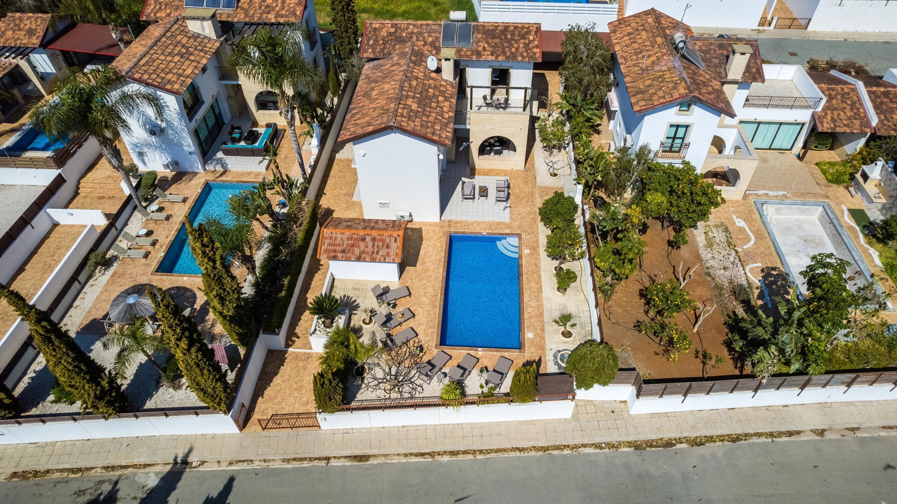 Vista aérea de una propiedad residencial con dos piscinas, un patio y un pequeño jardín.