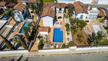 Vista aérea de una propiedad residencial con dos piscinas, un patio y un pequeño jardín.