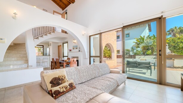 Ein geräumiger Wohnbereich mit einer Couch, einer Treppe und einer Schiebeglastür, die auf eine Außenpatio führt.