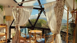 Une pièce dotée d'un plafond aux motifs géométriques, de meubles en osier et offrant une vue sur les montagnes.