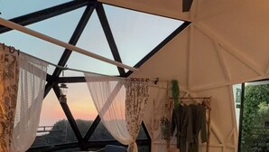 A tent-style room with a bed, a table, and chairs, a ceiling fan, and a view of the landscape. - Glamping Retreat Mountain Views, Proyector, Private Fire Pit and Kitchenette (Perez Zeledon)