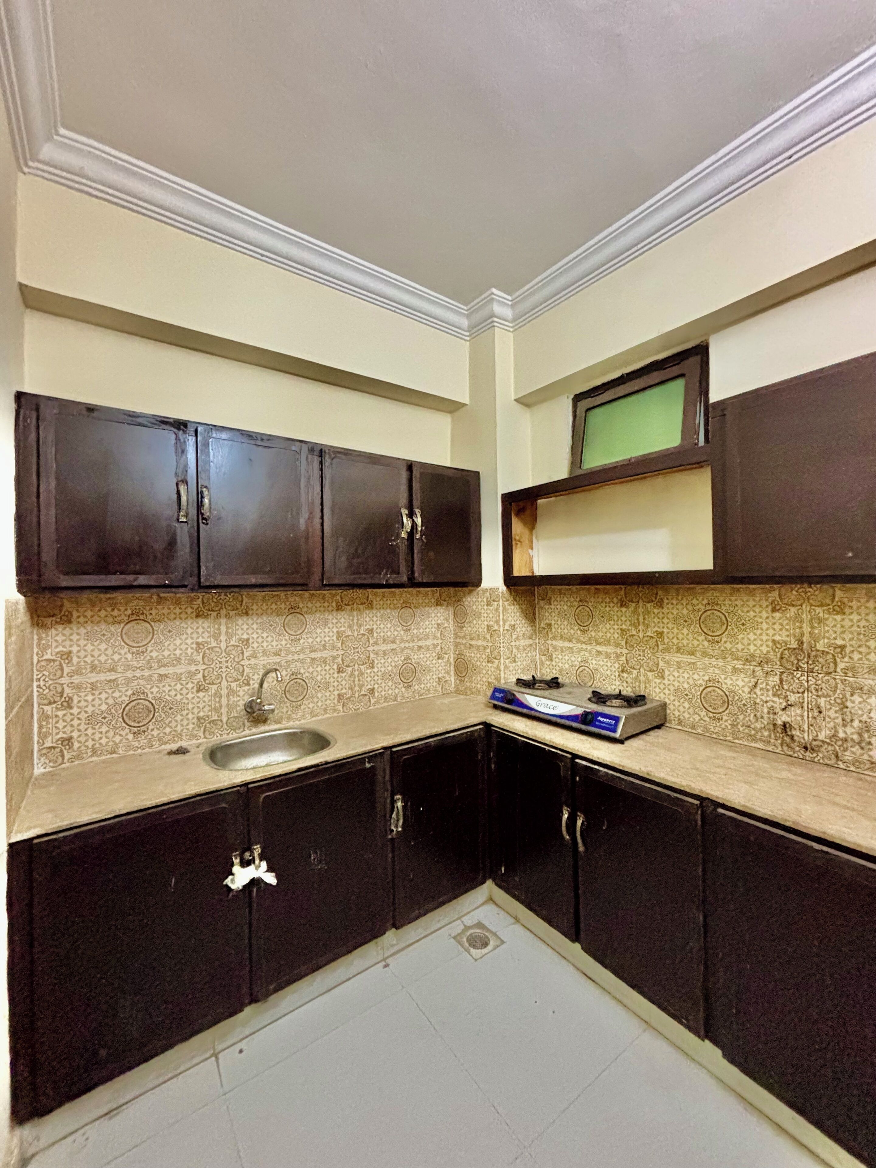 A compact kitchen with dark cabinets, a sink, and a microwave on a shelf.