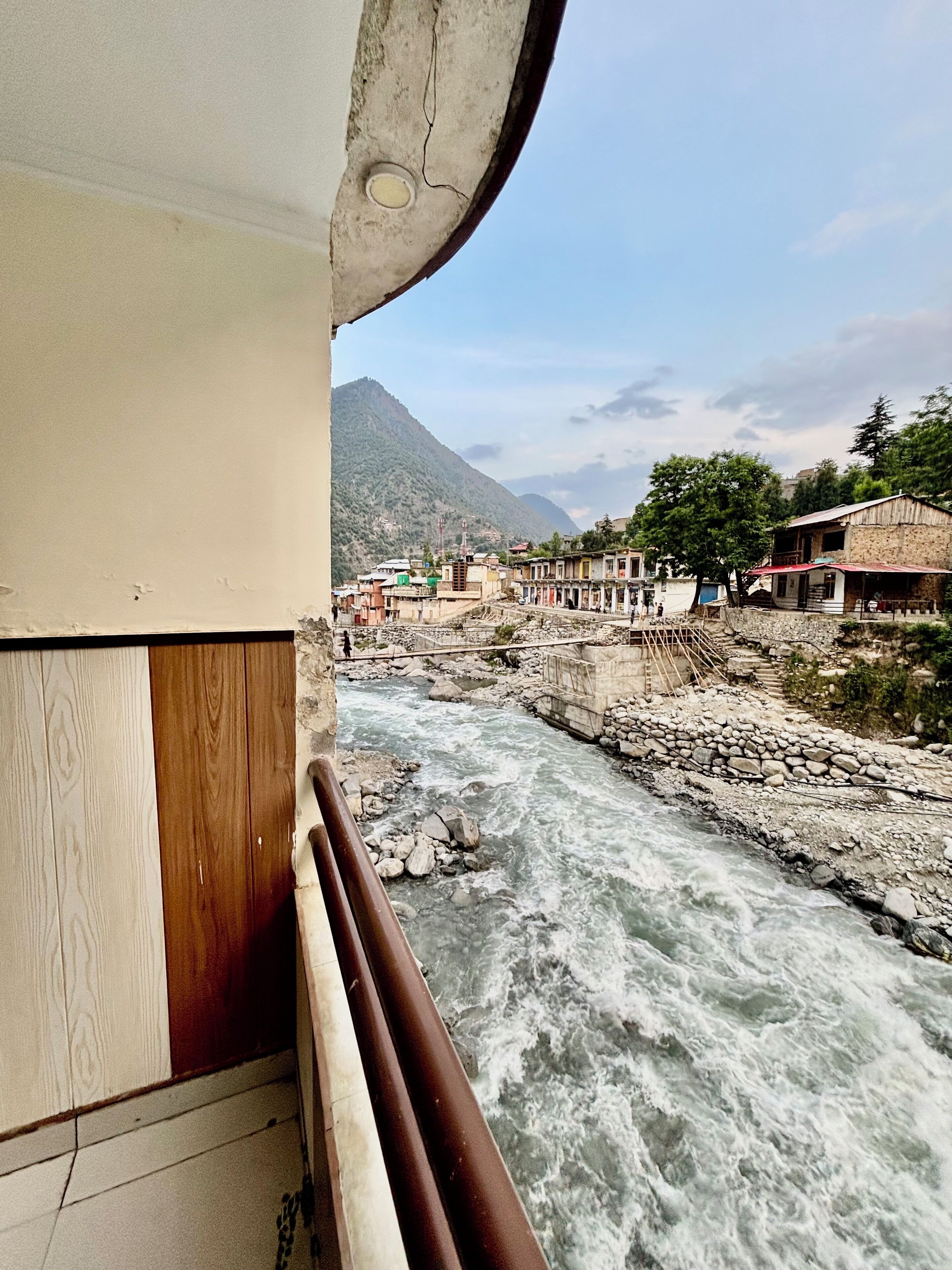 A river with a bridge, buildings, and mountains in the background.