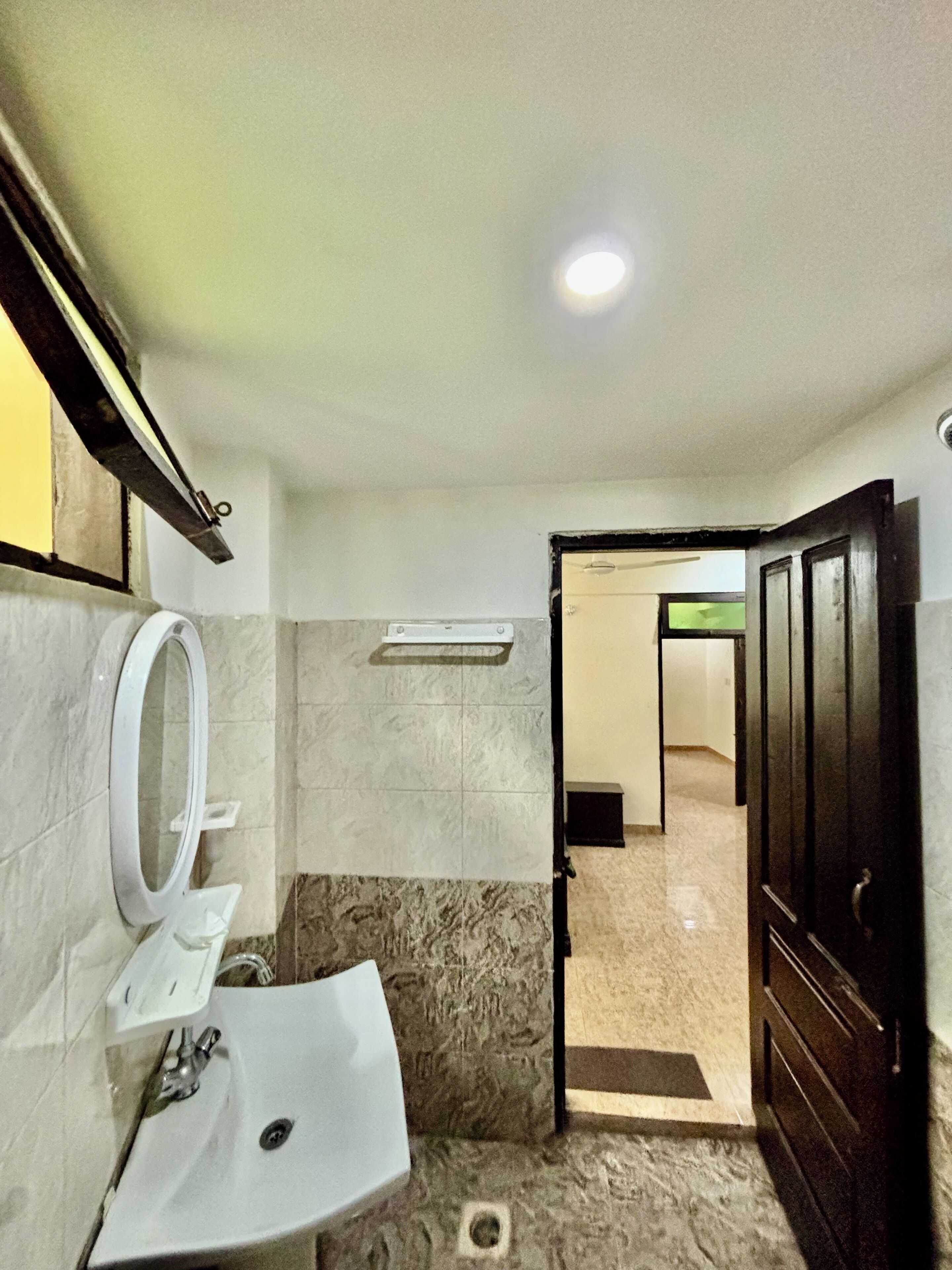 A bathroom with a sink, mirror, and a door leading to another room.