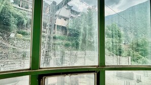 A view through a window with a stone wall and a metal structure in the background. - Torwal plaza and guest house  (Bahrain)
