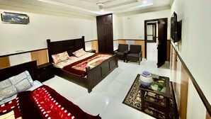 A bedroom with a bed, a desk, a chair, a wardrobe, and a television. - Torwal plaza and guest house  (Bahrain)
