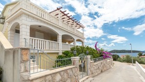 A two-story building with a balcony, stone wall, and a view of the sea.