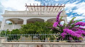 A building with a white facade, multiple arches, and a pergola on the upper level.