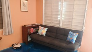Una sala de estar con un sofá, una estantería y un robot aspirador.