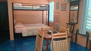 Un dormitorio con literas, un escritorio de madera, sillas, un espejo y un equipo de aire acondicionado.