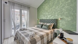A modern bedroom with a large bed, a green textured wall, and a view of the city. - Peaceful Blooming Villa with Pool - Four Bedroom Villa with Pool (Rovinj)