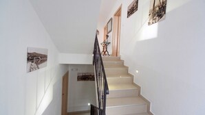 A staircase with beige steps and black railings, leading to a landing with a small table and a vase. - Beachfront Apartments for Relaxing Getaways in Crikvenica - Junior Studio Apartment 2 2 (Crikvenica)