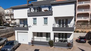 Un edificio moderno de dos pisos con balcones, un garaje y un pequeño jardín.