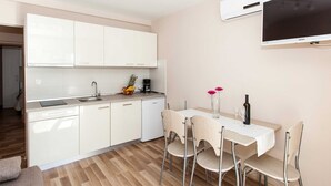 Una cocina moderna con armarios blancos, lavavajillas integrado y un comedor con mesa y sillas.
