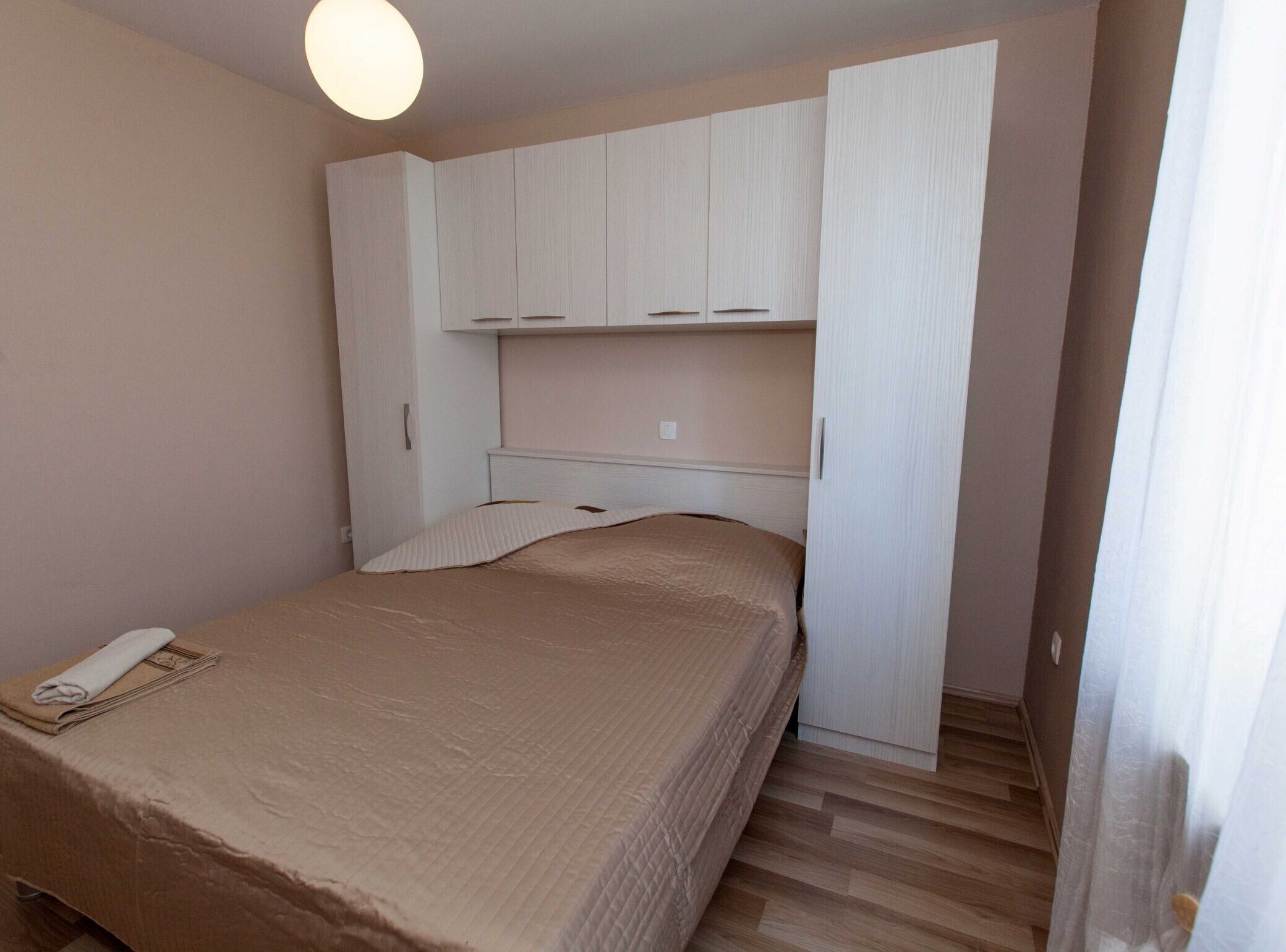 Ein Schlafzimmer mit Bett, Nachttisch, Kleiderschrank und Deckenleuchte.