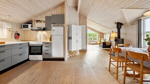Una cocina moderna con pisos de madera, un comedor con mesa y sillas, y un ventanal que proporciona luz natural.