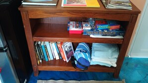 A wooden shelf with books, a bicycle repair kit, and board games.